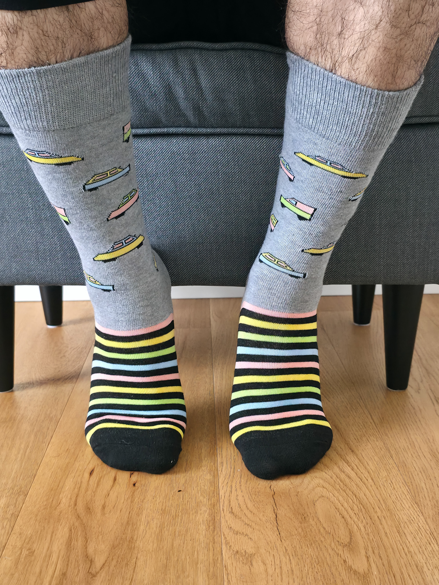 Primer plano de una persona vistiendo calcetines navideños de color verde con estampado de sellos postales festivos, regalos y matasellos "Happy Holidays".